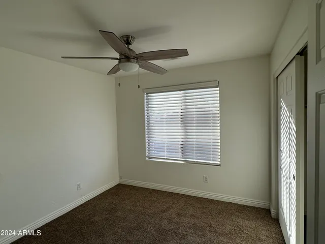 an empty room with a window and a fan