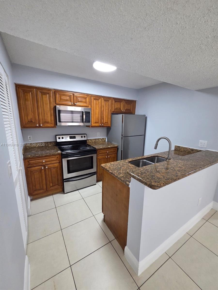 1241 Southwest 46th Avenue, Unit 1006 Pompano Beach, FL 33069 - Photo 1 of 9 a kitchen with granite countertop a stove top oven and cabinets