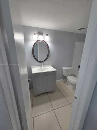 a bathroom with a toilet mirror vanity and sink