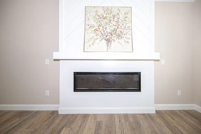 a view of empty room with wooden floor and a fireplace