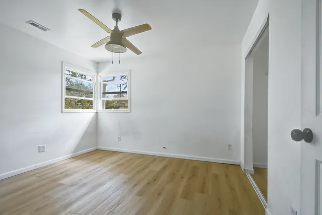 an empty room with wooden floor and ceiling fan