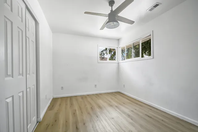 an empty room with wooden floor and ceiling fan