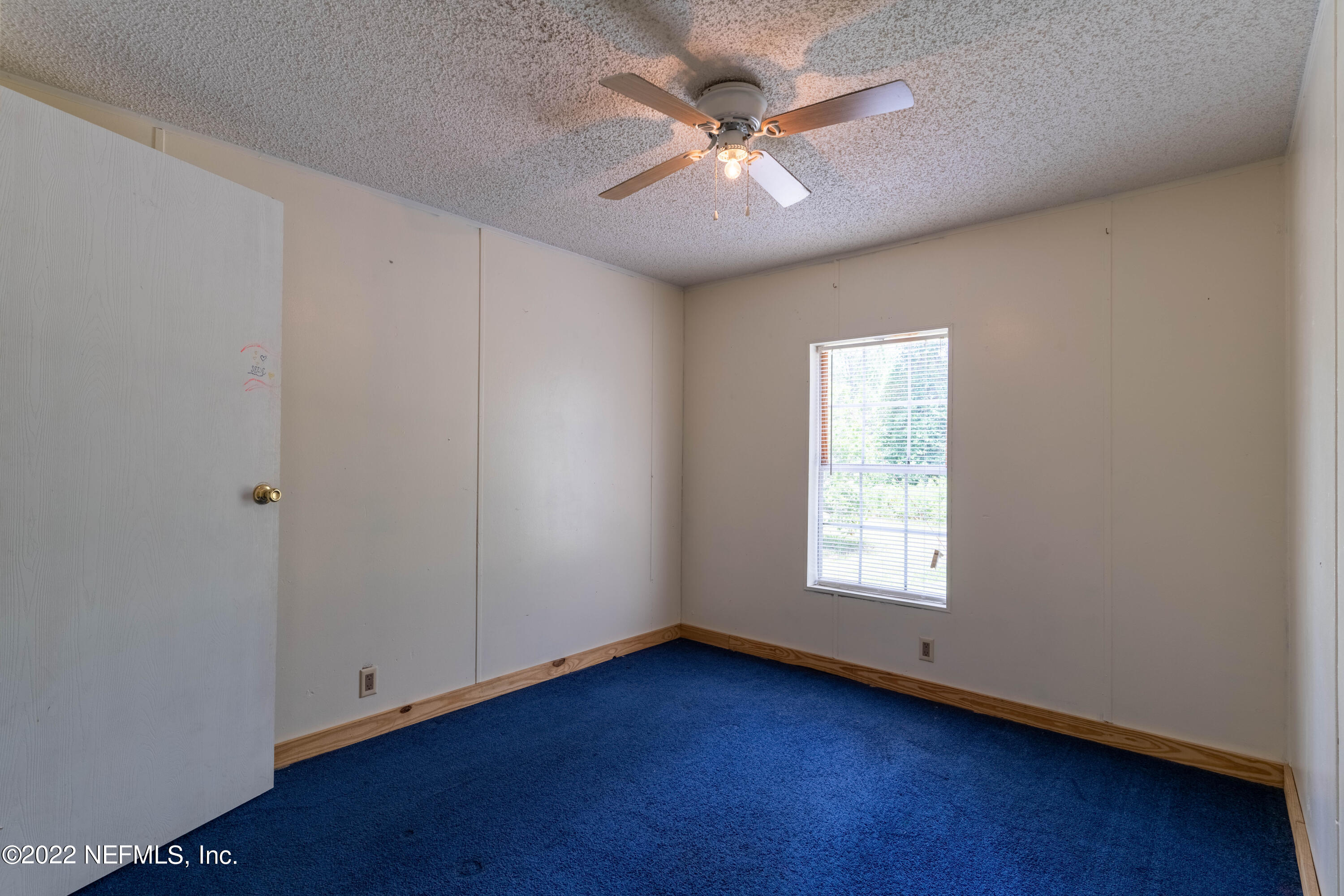 19697 Crews Road Glen St. Mary, FL 32040 - Photo 21 of 25 an empty room with wooden floor chandelier fan and windows