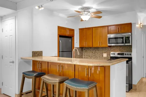 a kitchen with stainless steel appliances granite countertop a stove a sink dishwasher and a refrigerator with wooden floor