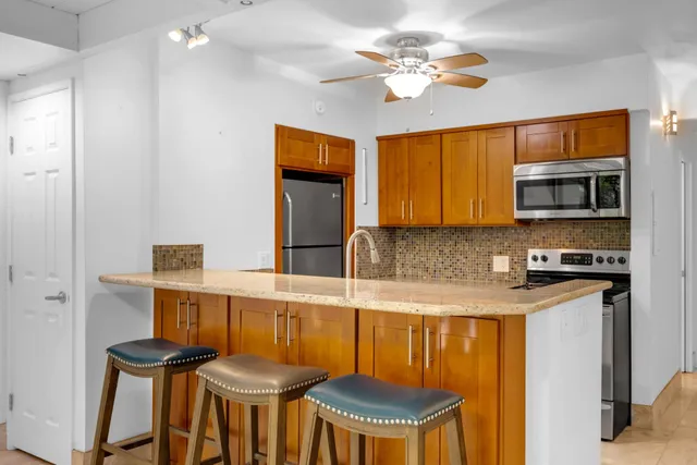 a kitchen with stainless steel appliances granite countertop a stove a sink dishwasher and a refrigerator with wooden floor