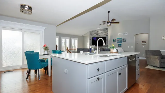 a room with stainless steel appliances kitchen island granite countertop a dining table chairs and a refrigerator