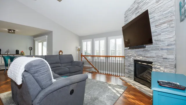 a living room kitchen with stainless steel appliances furniture wooden floor and a view of kitchen