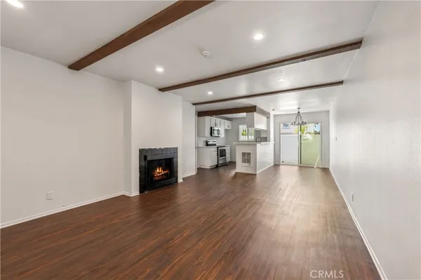 an empty room with wooden floor fireplace and windows
