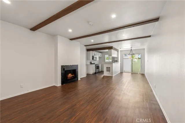 an empty room with wooden floor fireplace and windows