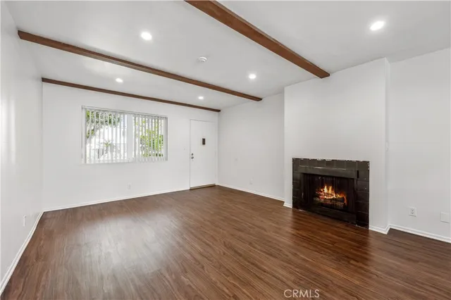 an empty room with wooden floor fireplace and window