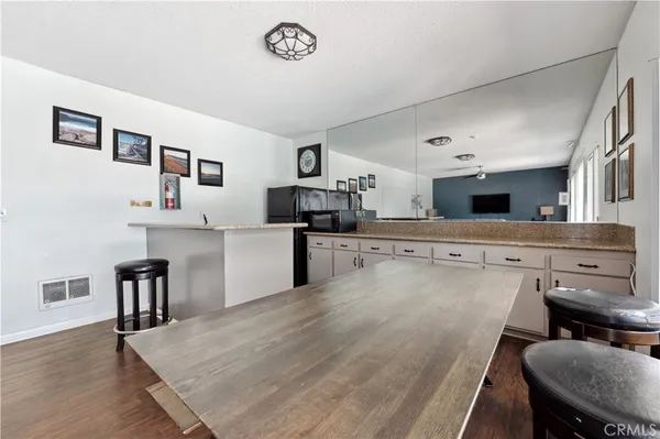 a open kitchen with stainless steel appliances granite countertop a stove top oven a sink a dining table and chairs with wooden floor