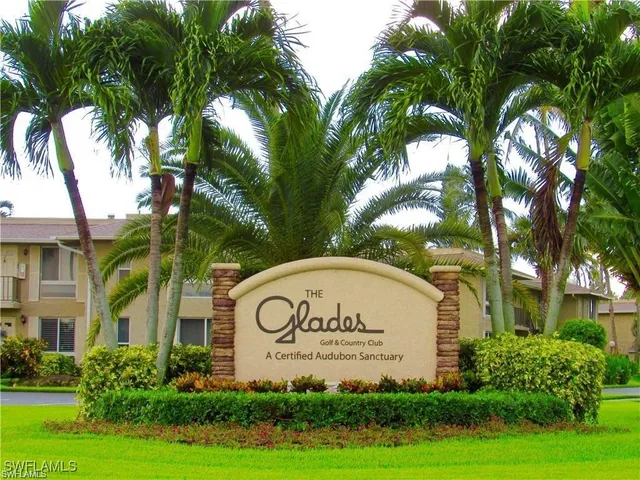 a sign of golf club on a wall under a tree