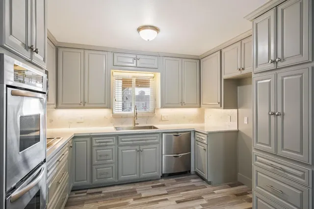 a kitchen with stainless steel appliances granite countertop a sink and dishwasher a refrigerator with wooden cabinets