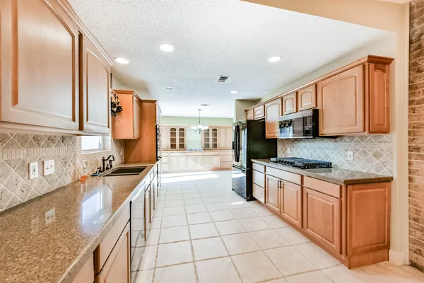 a large kitchen with stainless steel appliances granite countertop a stove a sink and a microwave