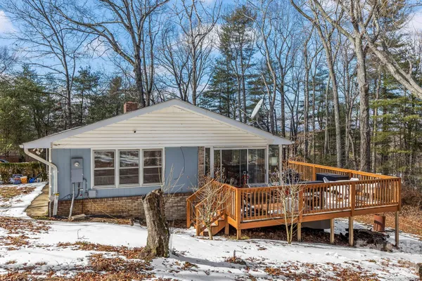 a view of a house with a wooden bench in a backyard