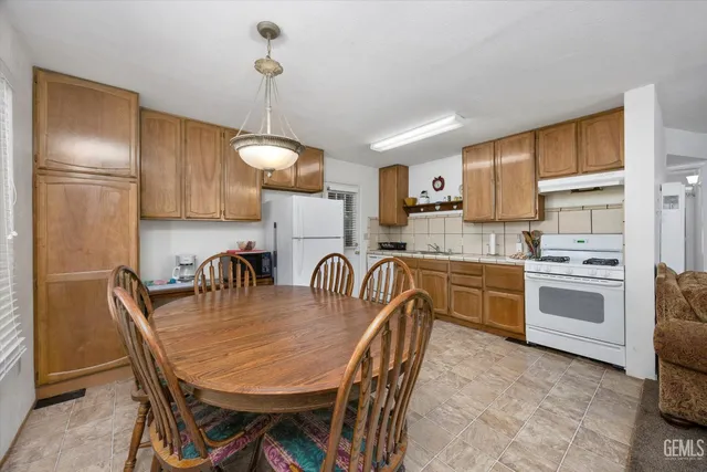 a kitchen with granite countertop a stove a sink a dining table and chairs