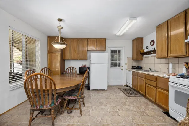 a kitchen with refrigerator a sink dining table and chairs