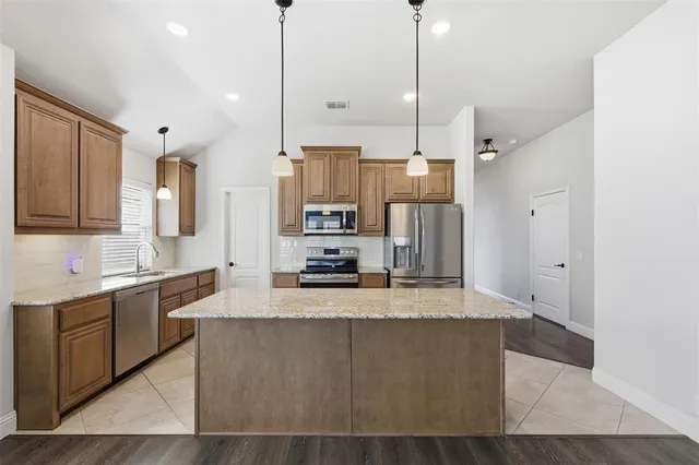 a large kitchen with granite countertop a sink a counter space appliances and cabinets