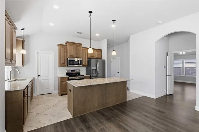 a large kitchen with stainless steel appliances kitchen island granite countertop a sink a stove and a wooden floors