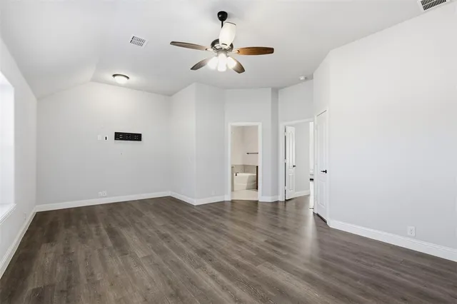 an empty room with wooden floor ceiling fan and windows