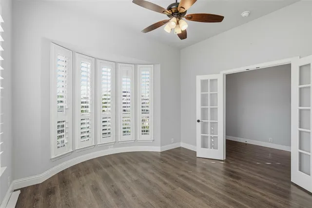 an empty room with wooden floor closet and windows