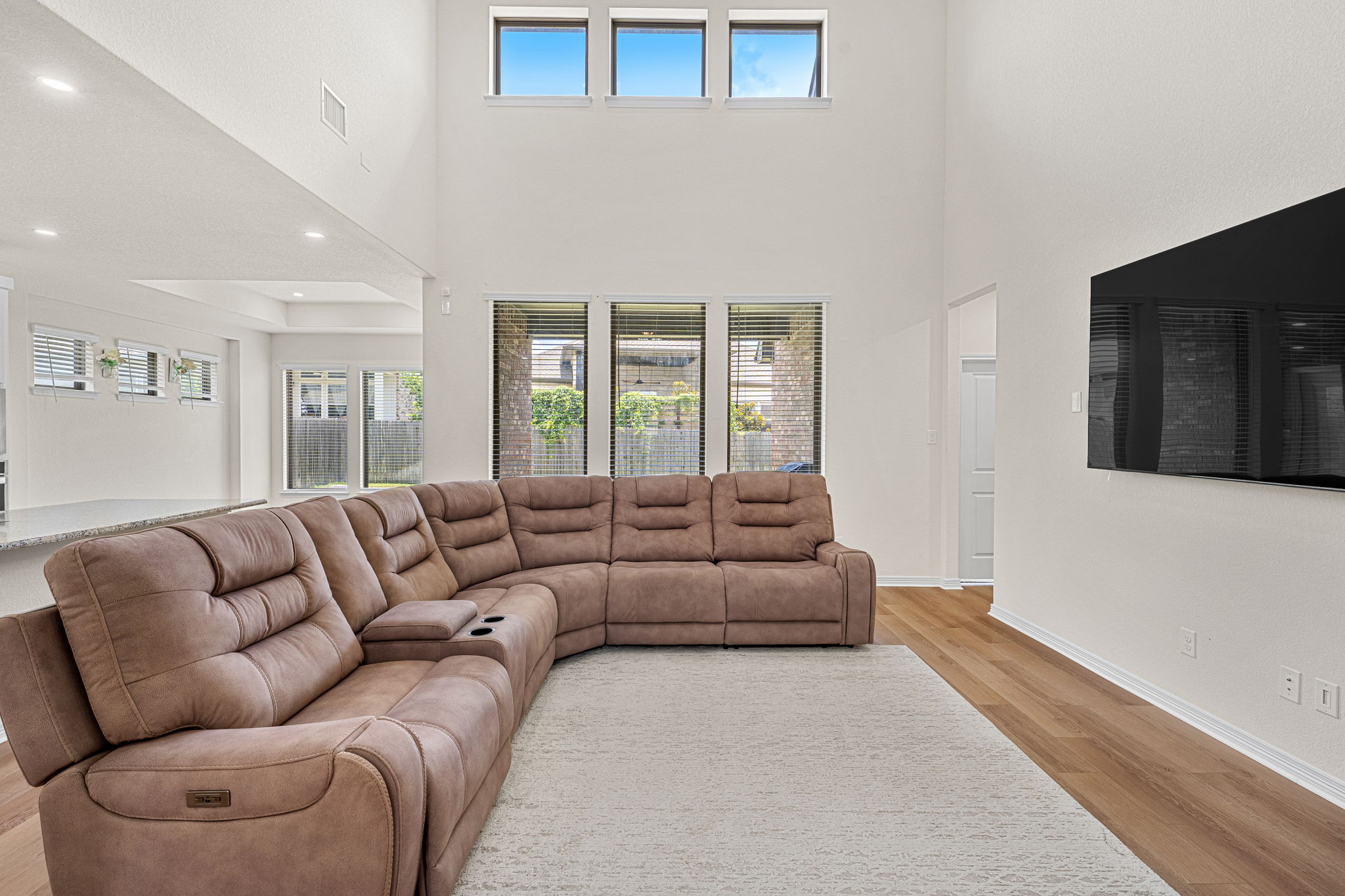 20813 Carries Ranch Road Pflugerville, TX 78660 - Photo 7 of 40 Double-height ceilings and tall windows illuminate a spacious main level with light-toned wood floors.
