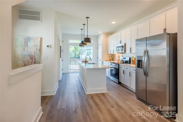 a kitchen with kitchen island wooden floors white appliances and cabinets
