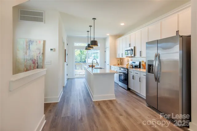 a kitchen with kitchen island wooden floors white appliances and cabinets