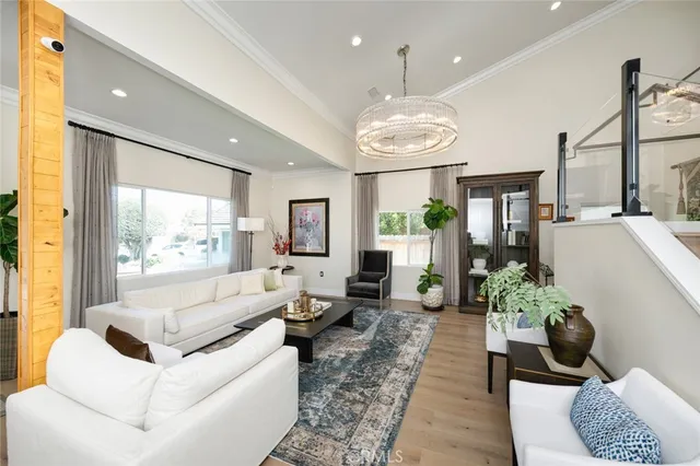 a living room with stainless steel appliances furniture a large window and a kitchen view