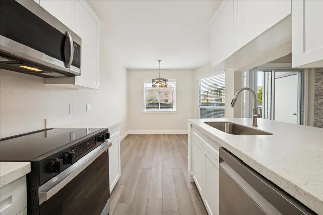 a kitchen with stainless steel appliances granite countertop a sink a stove and a microwave oven with cabinets