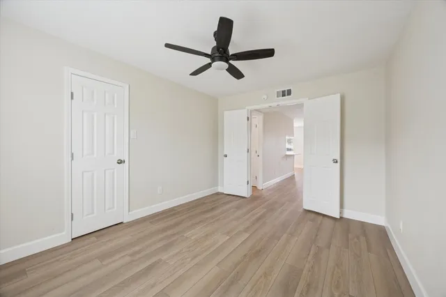 a view of empty room with wooden floor and ceiling fan
