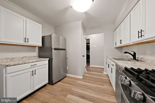 a kitchen with granite countertop white cabinets and stainless steel appliances