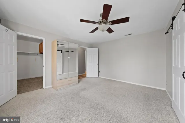 a view of a livingroom with a ceiling fan & windows
