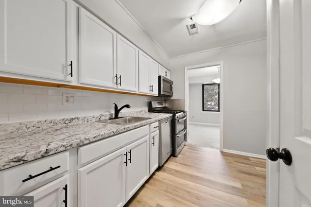 a kitchen with granite countertop a sink stainless steel appliances and cabinets