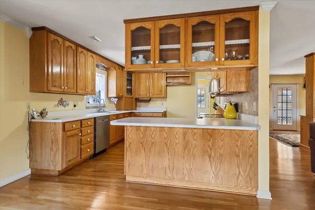 a kitchen with stainless steel appliances a stove a sink a microwave a refrigerator cabinets and a dining table