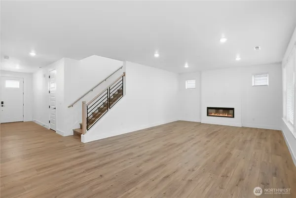 a view of an empty room with wooden floor and stairs