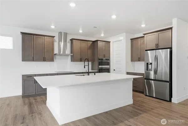 a large kitchen with stainless steel appliances a refrigerator and a stove top oven