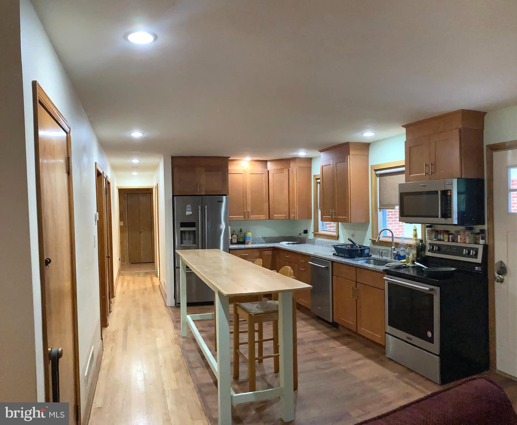1713 Cape May Road Baltimore, MD 21221 - Photo 11 of 34 a kitchen with stainless steel appliances granite countertop a stove top oven a sink dishwasher a refrigerator and a dining table with wooden floor