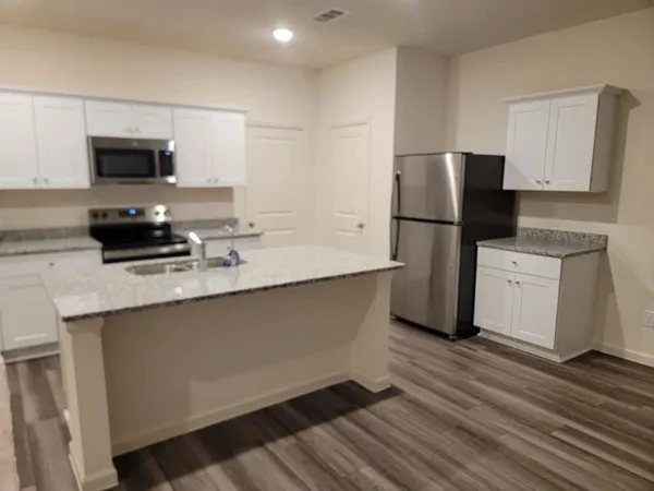 a kitchen with a sink a refrigerator and white cabinets