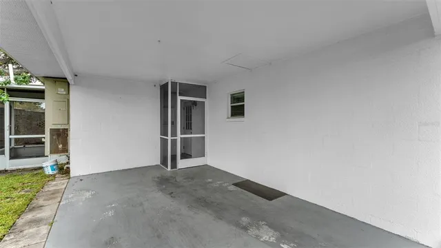 a view of an empty room with wooden floor and a kitchen