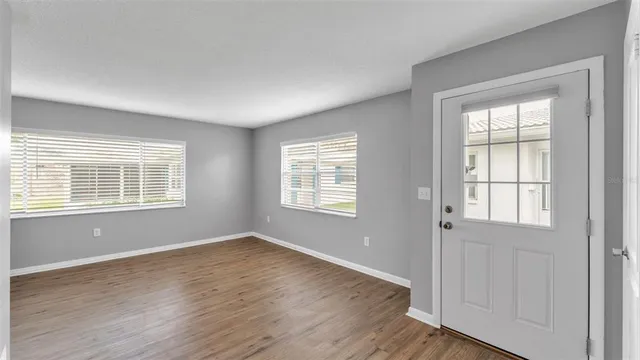 an empty room with wooden floor and windows