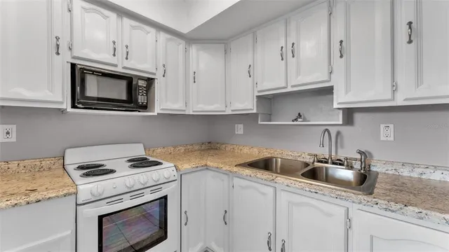 a kitchen with granite countertop white cabinets white stainless steel appliances and a sink