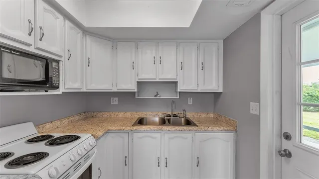 a kitchen with granite countertop a stove sink and cabinets