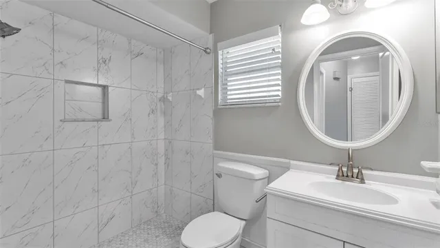a bathroom with a toilet sink mirror vanity and window