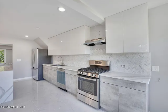 a kitchen with stainless steel appliances white cabinets and a stove top oven