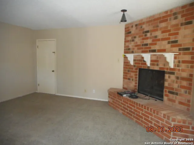 a view of an empty room with wooden floor and a fireplace