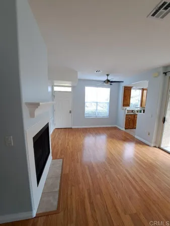 an empty room with wooden floor fireplace and windows