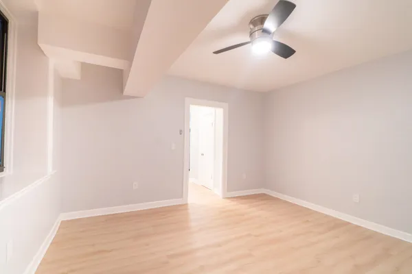 an empty room with ceiling fan and window