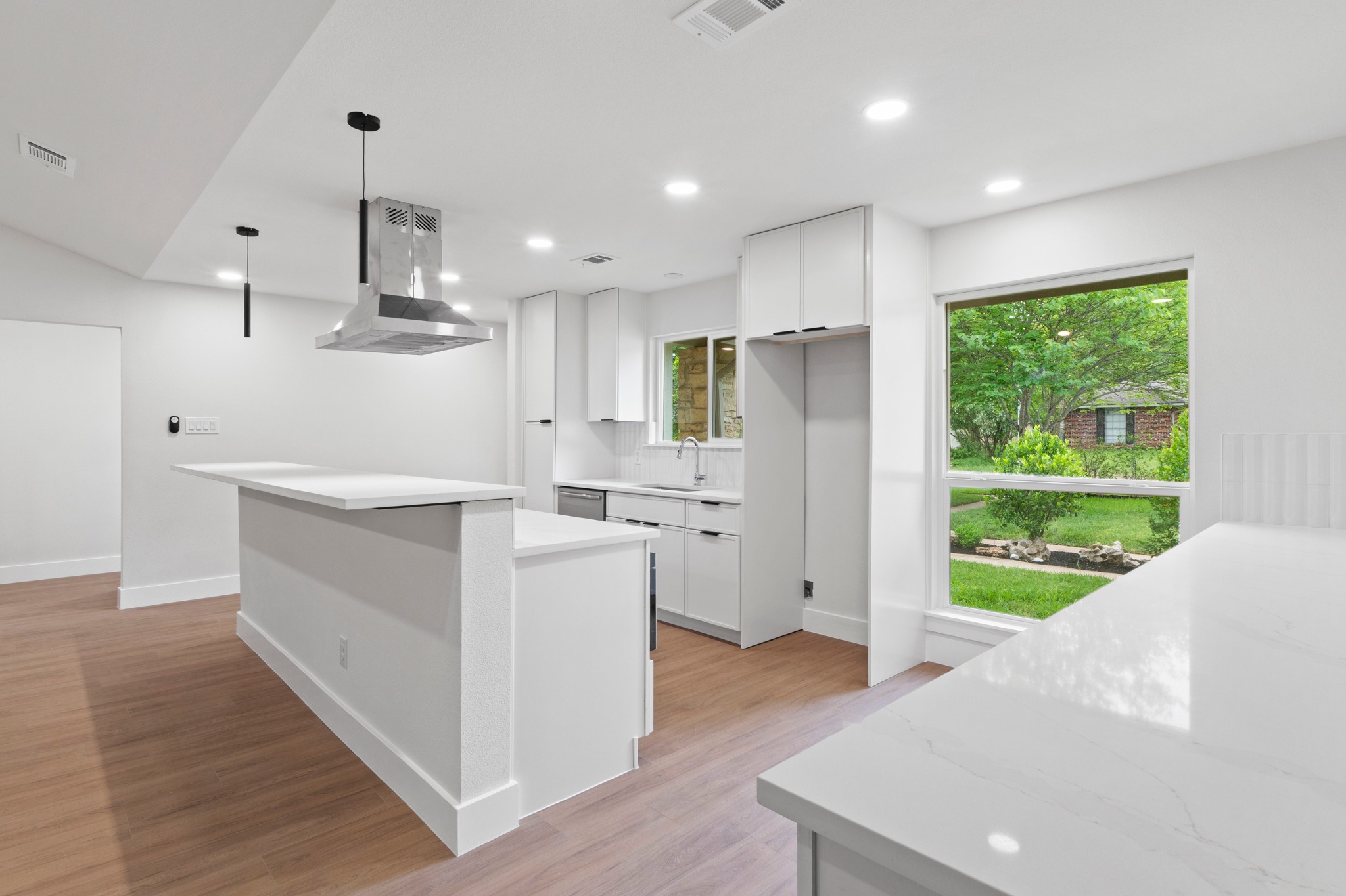 1608 Springer Lane Austin, TX 78758 - Photo 26 of 35 Modern kitchen featuring a large center island, white cabinetry, integrated stainless steel range hood, recessed lighting, and wood-finish flooring