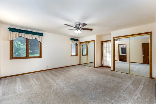 an empty room with chandelier fan and windows